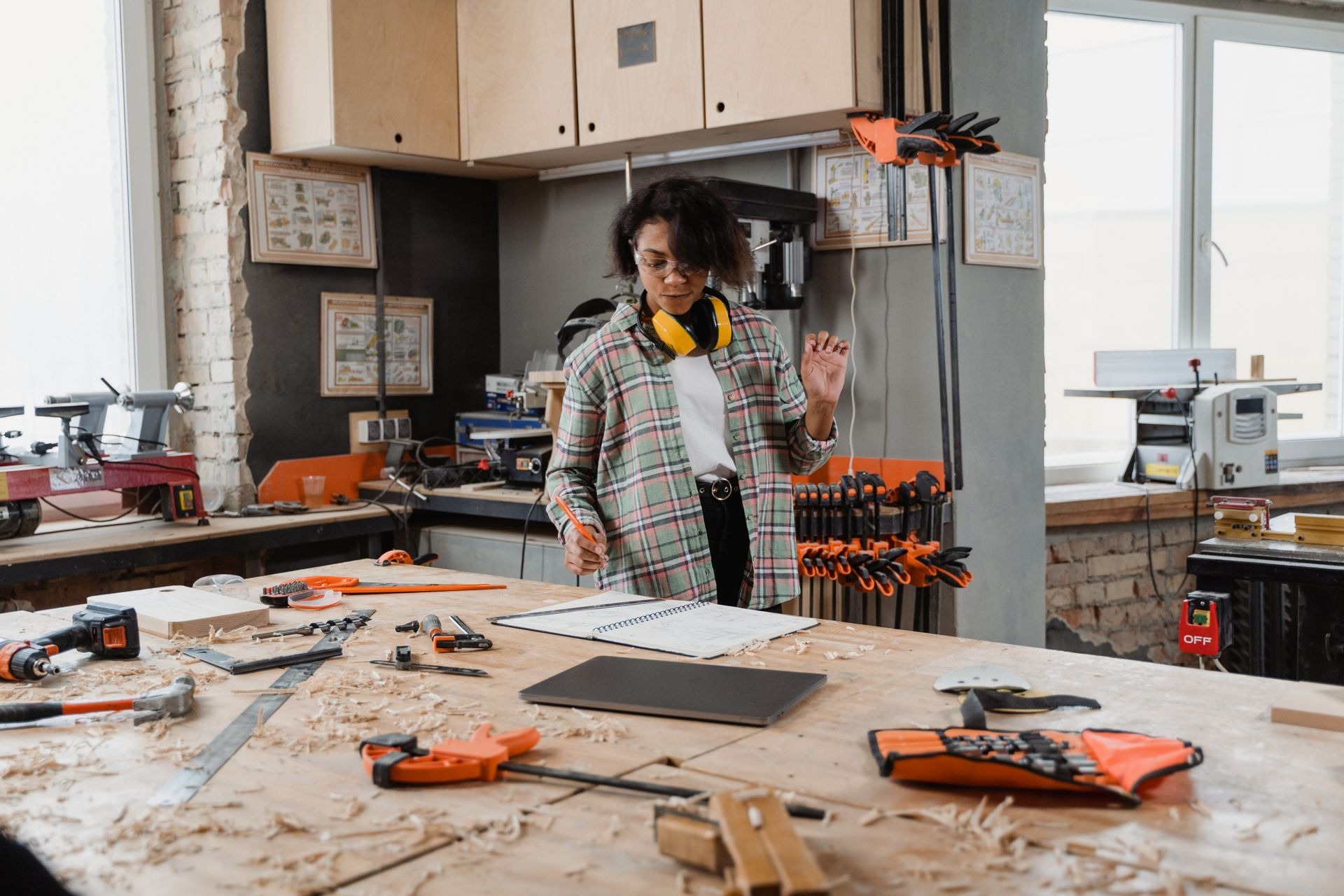 A woman in a woodworking workshop with tools and notes