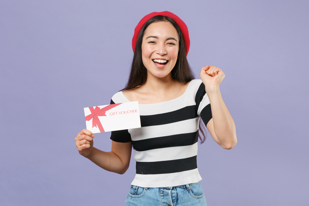 Happy woman celebrating with a Go Local gift voucher in hand.