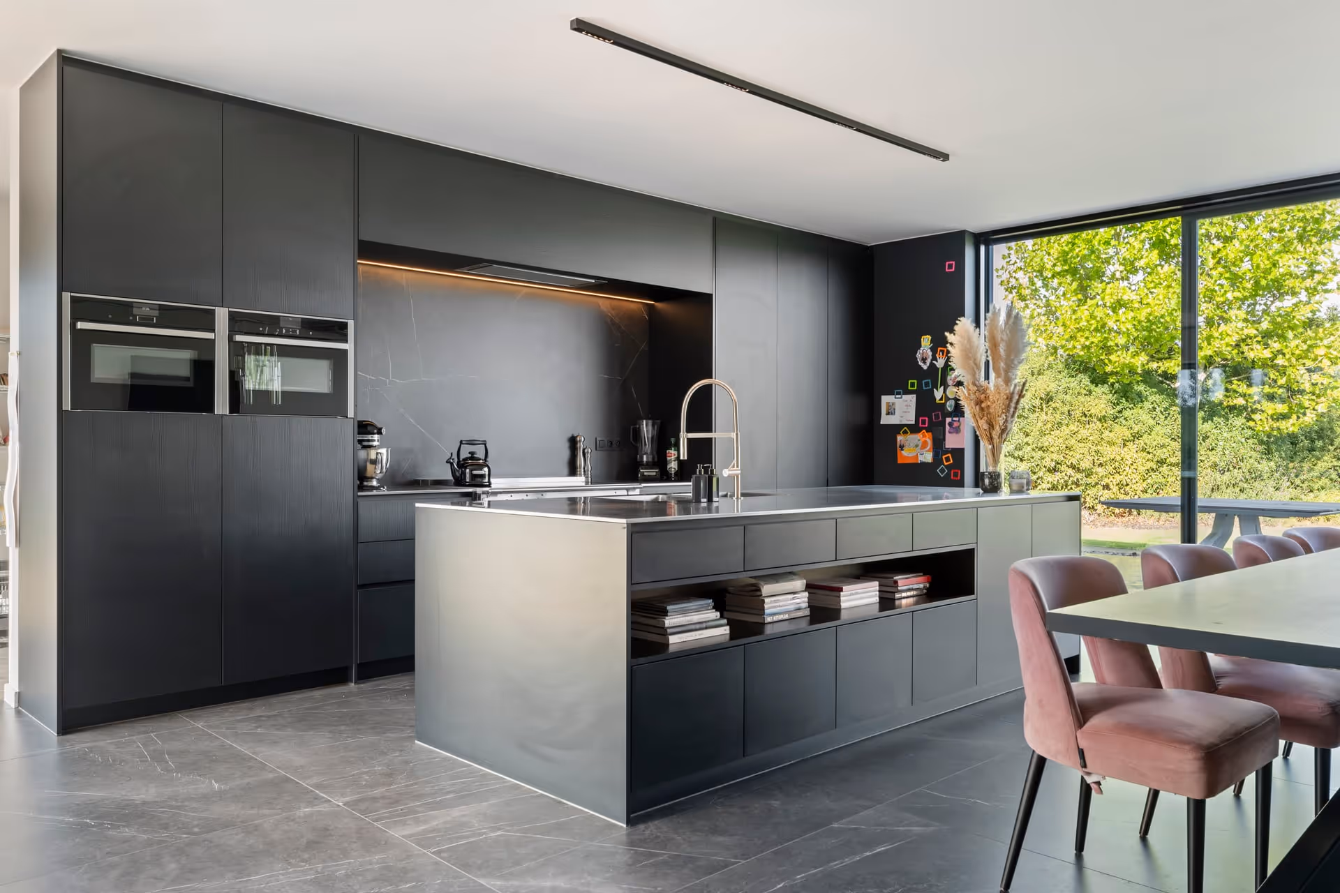 Interieurfotografie van een donkere, zwarte keuken met groot raam en luxe afwerking.
