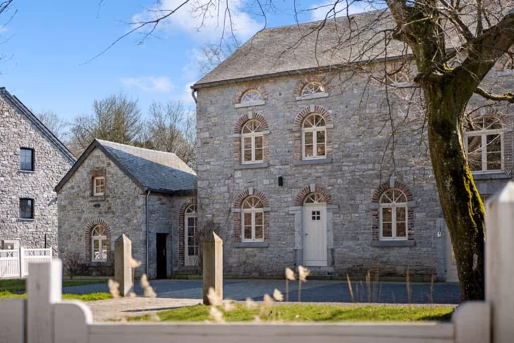 Exterieur vastgoedfotografie van een charmant, authentiek stenen huis met ramen en een lichte voordeur.