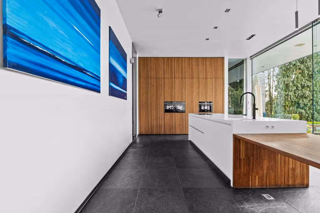 Strakke interieurfotografie van een moderne hal die leidt naar een keuken met een houten wandpaneel.