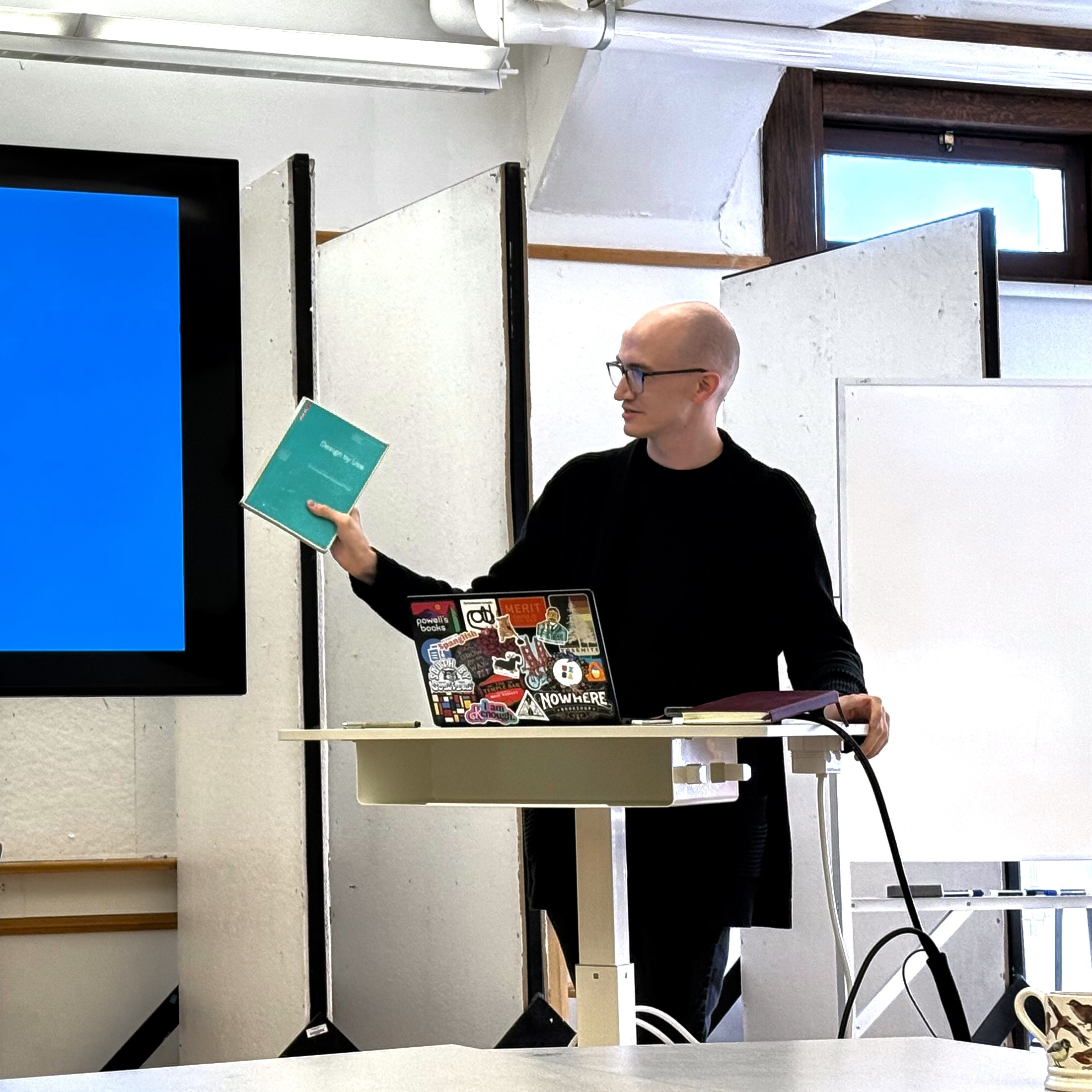 A photo of Joseph Ratliff giving a presentation while holding a book