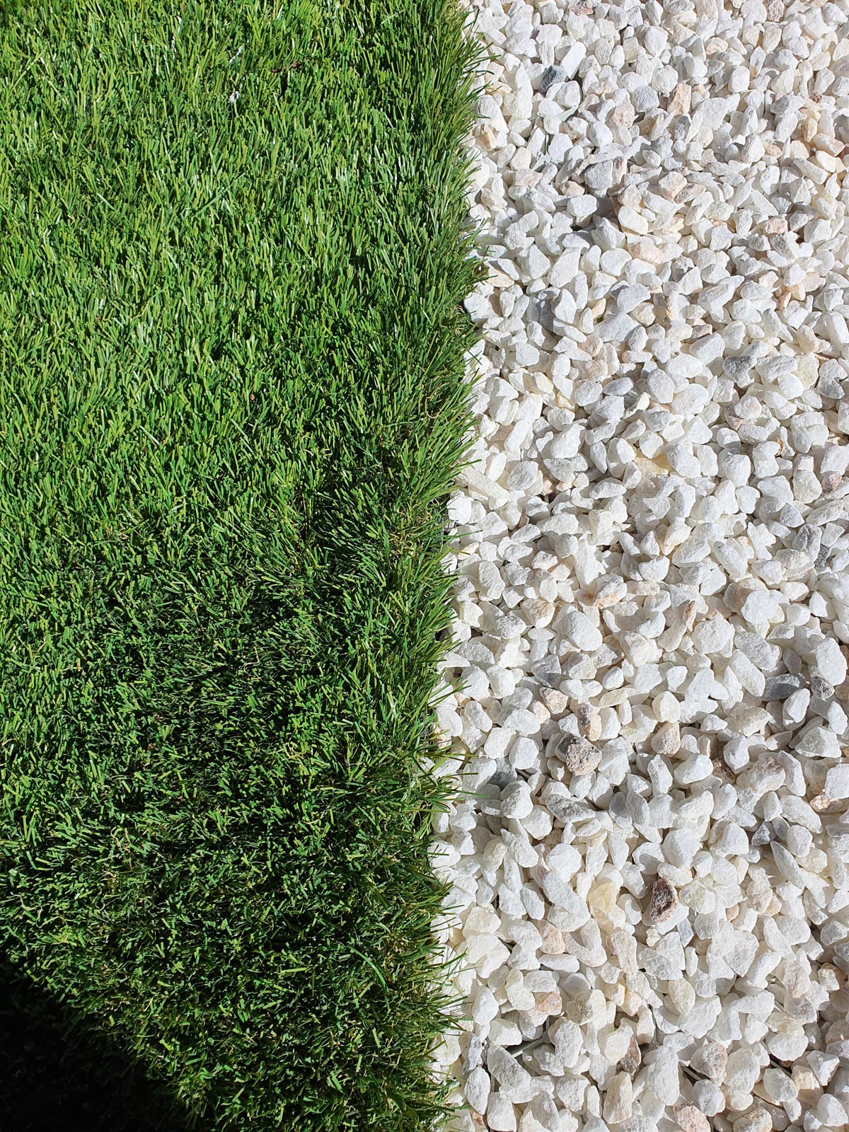 Détail entre gazon synthétique et gravier décoratif pour jardin à Marseille.