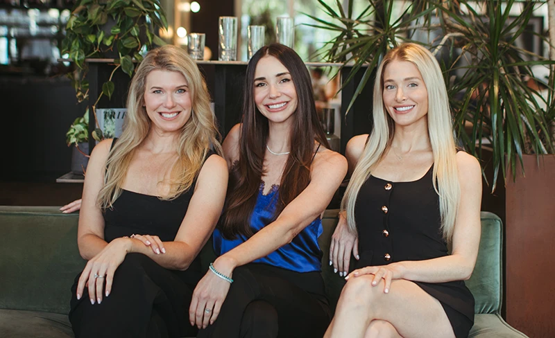 Photo of Blaine and her teammates Ash and Steph seated on a couch.