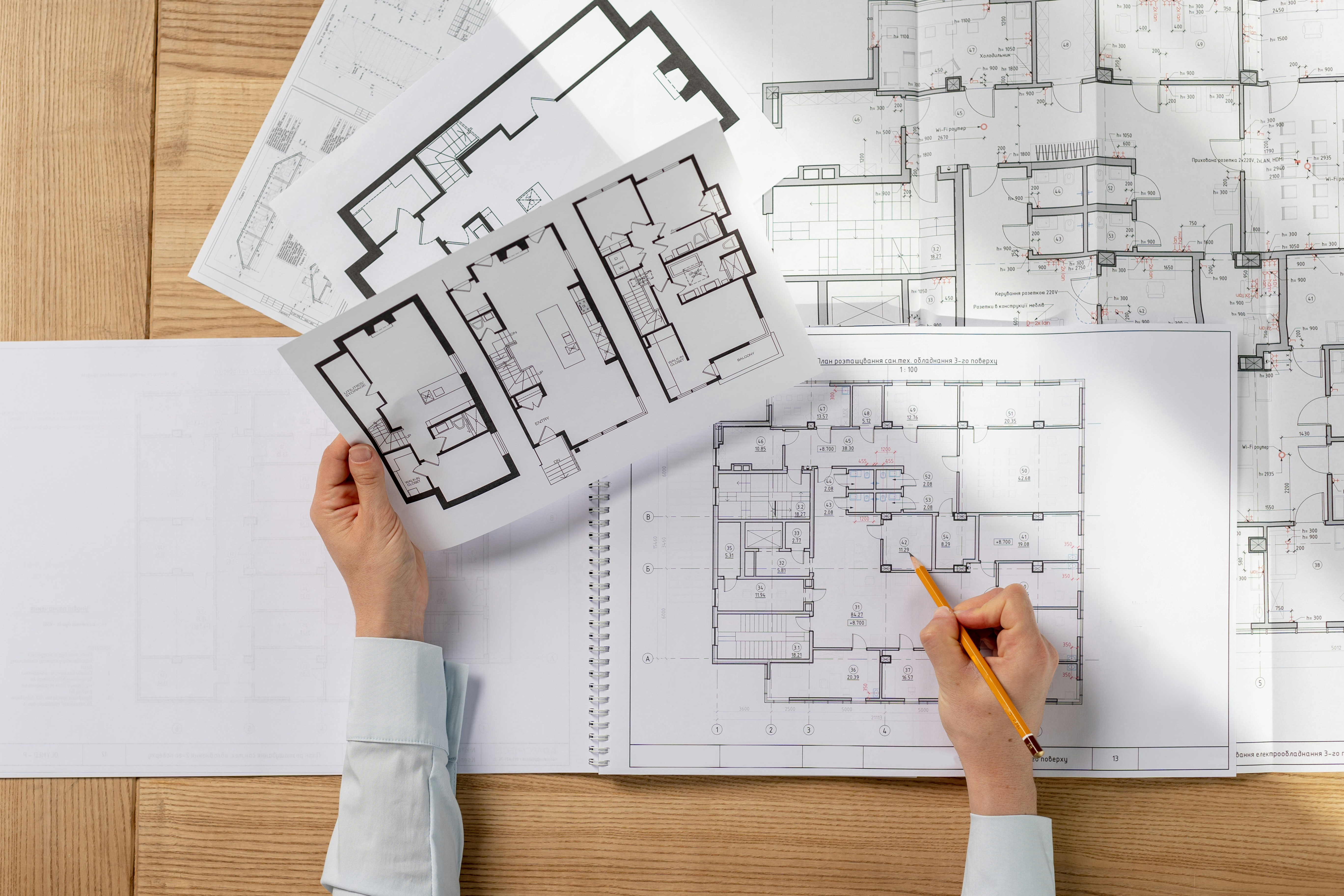 Hände eines Architekten halten die Unterlagen für den Bauantrag