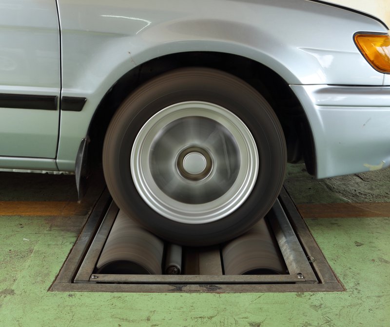 Gros plan sur une roue de voiture en rotation sur un banc d'essai dans un centre de contrôle technique.