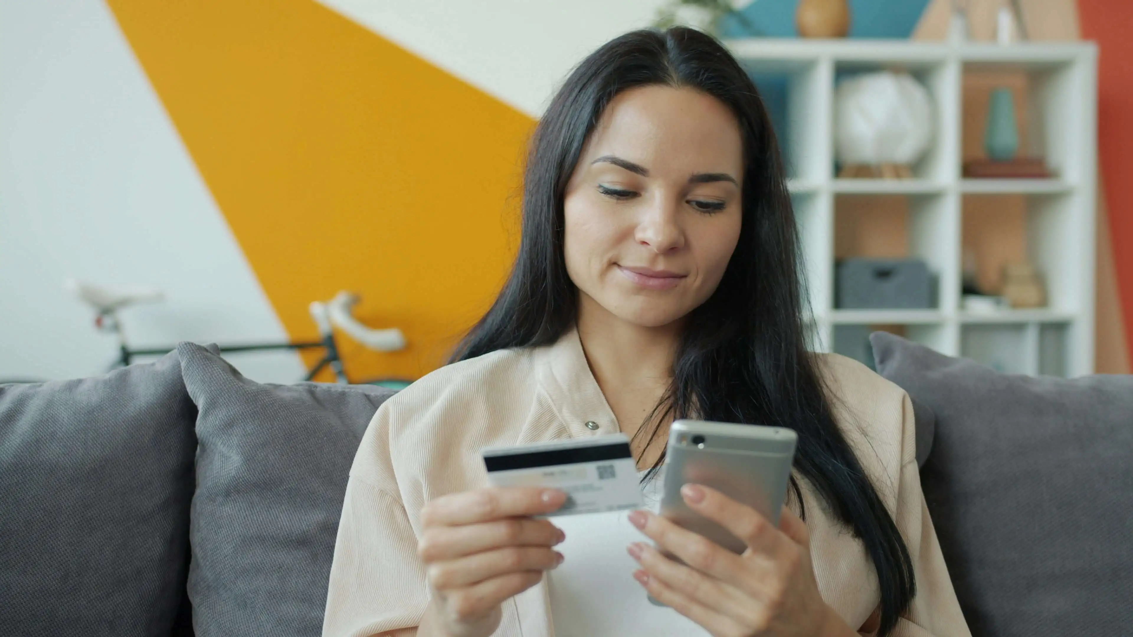 Woman holds debit card and phone