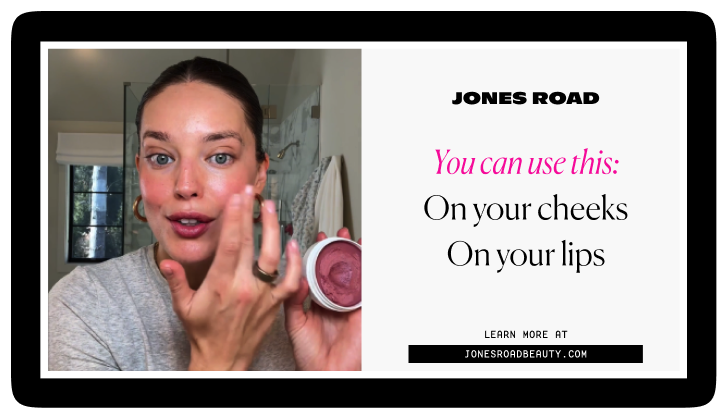 Woman applying pink cream blush on her cheek with fingertip, holding a jar of the product, next to text promoting Jones Road blush for cheeks and lips.