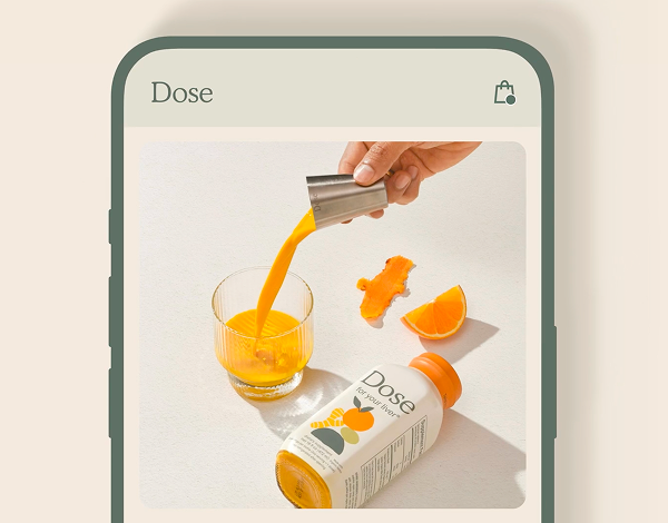 Hand pouring orange liquid from a small metal cup into a glass next to a Dose liquid supplement bottle and orange fruit pieces.