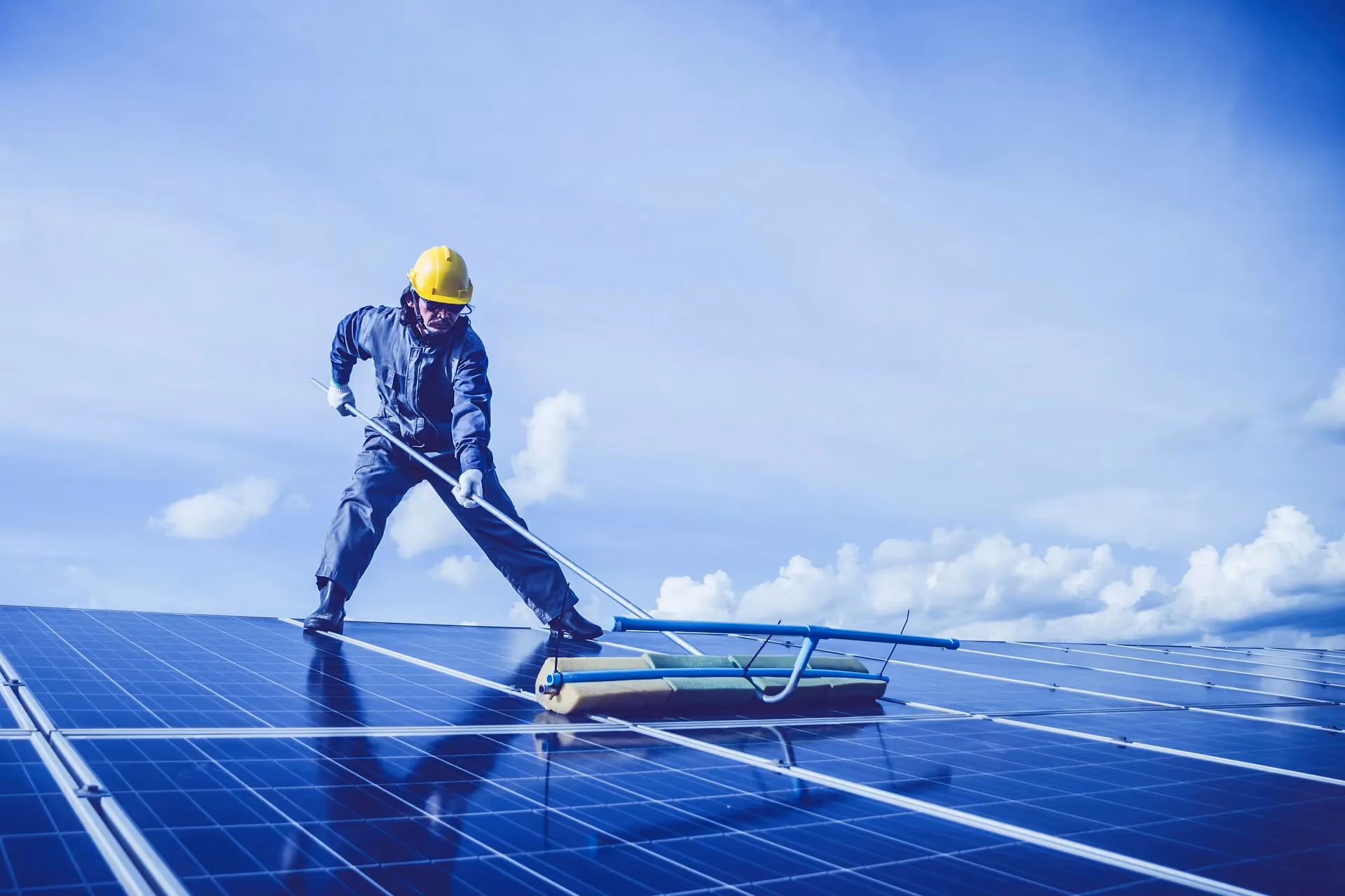 A man cleaning solar panels with a broom.