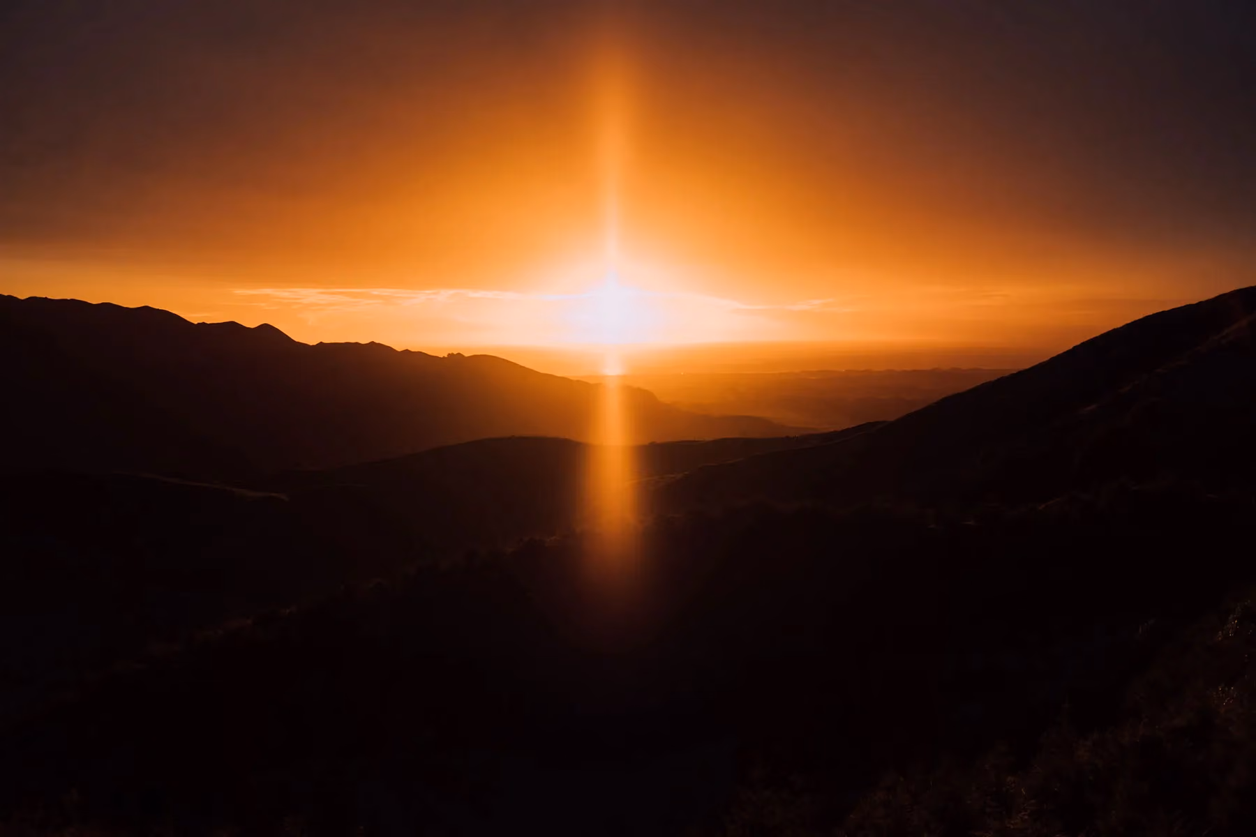 The sun is setting over a mountain in the background in New Zealand.