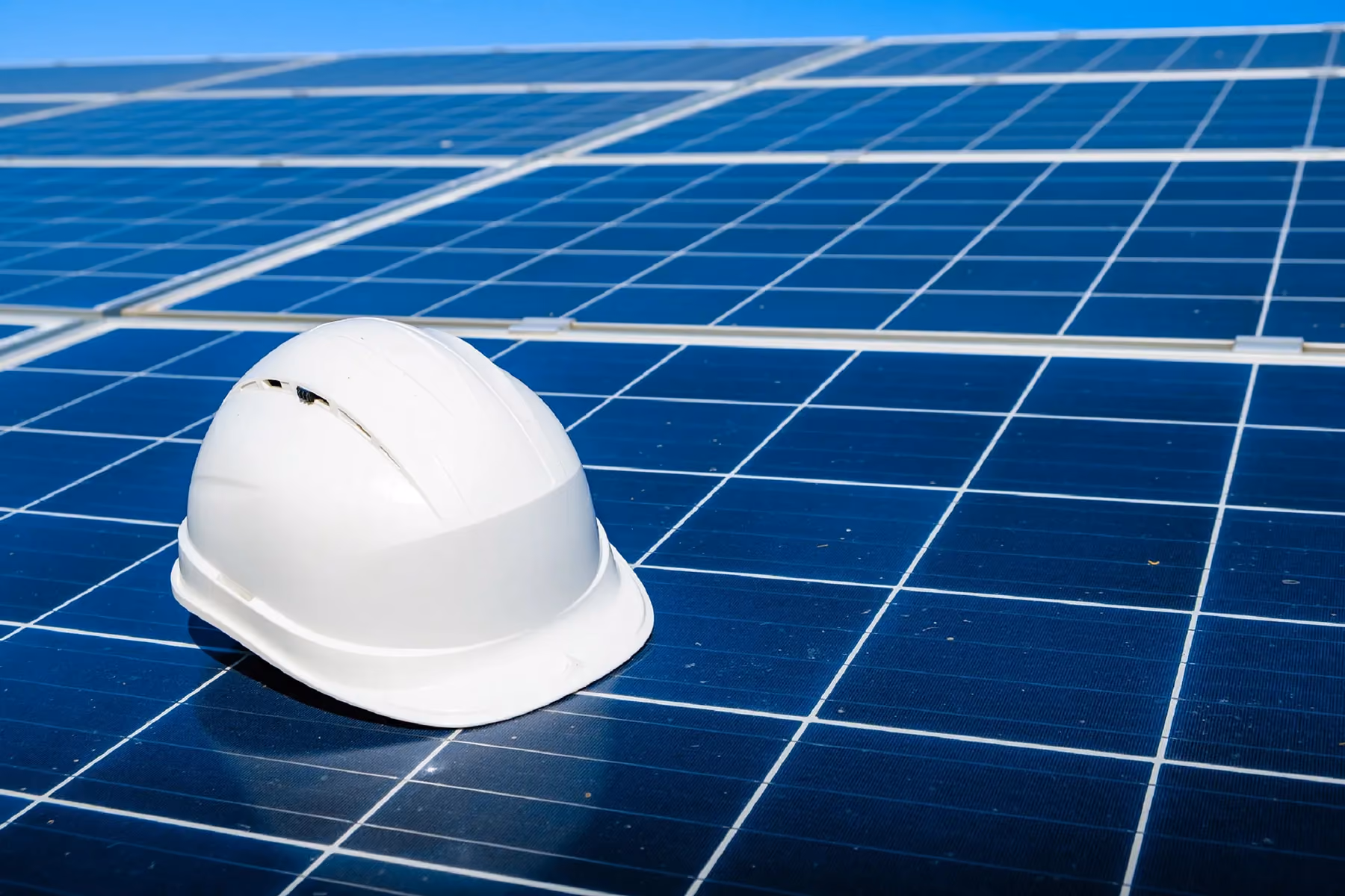 A hard hat sits on top of solar panels.