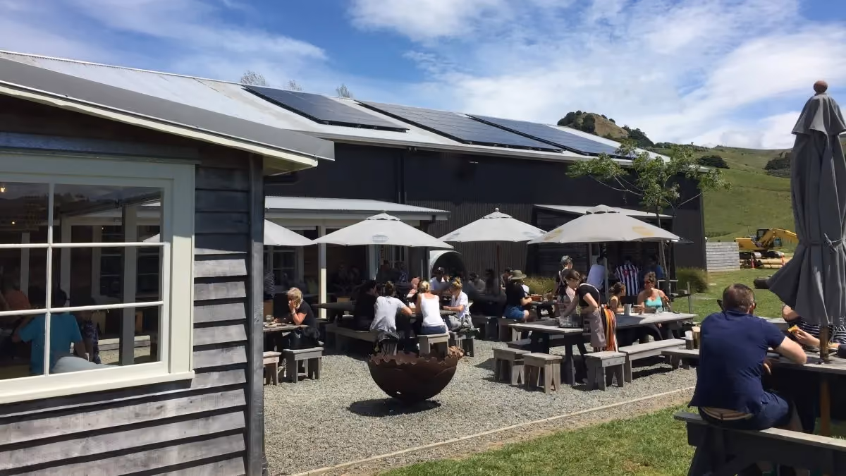 A group of people sitting at tables outside at Sawmill Brewery & Cafe, New Zealand.
