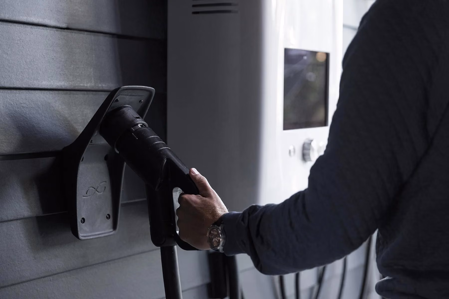 A man is charging his electric car at a charging station.