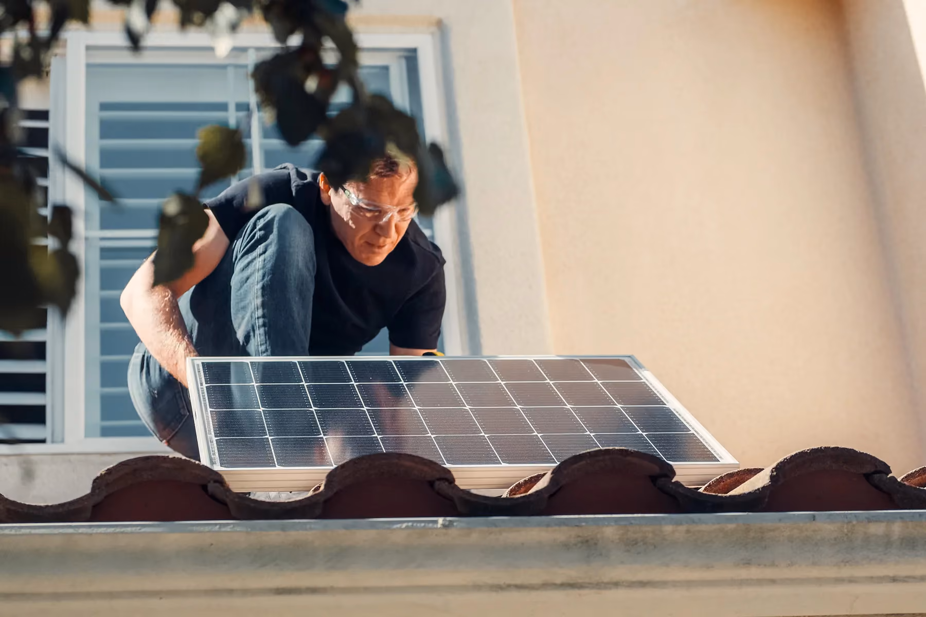 A man installing solar panels on the roof of a house.