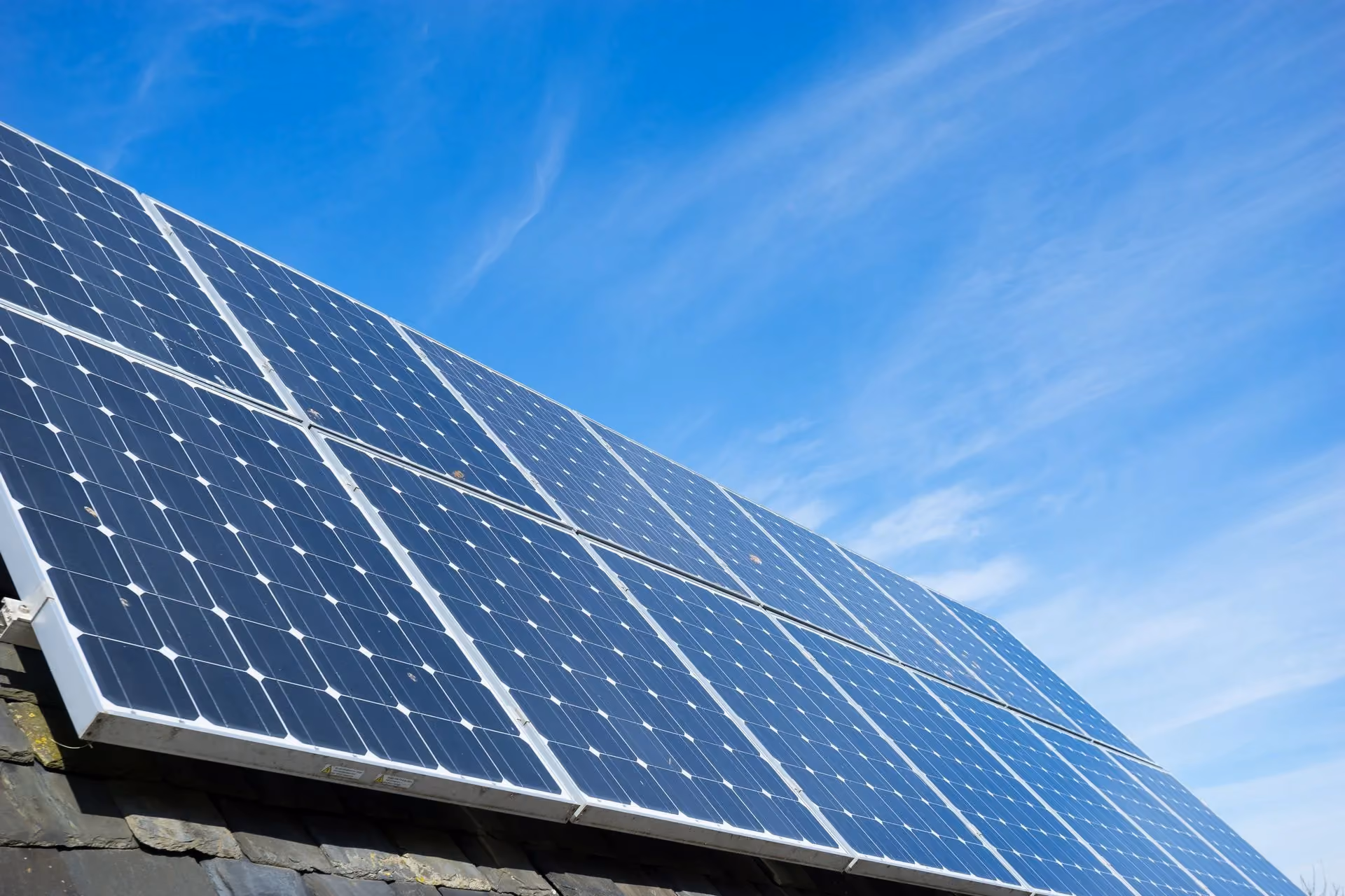Solar panels on a roof against a blue sky.