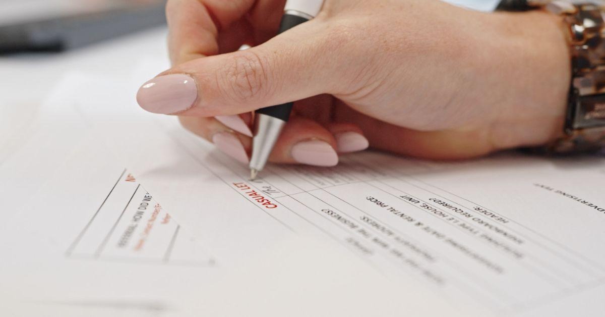 Property manager filling in a rental property form with a pen, documenting details for a landlord insurance claim