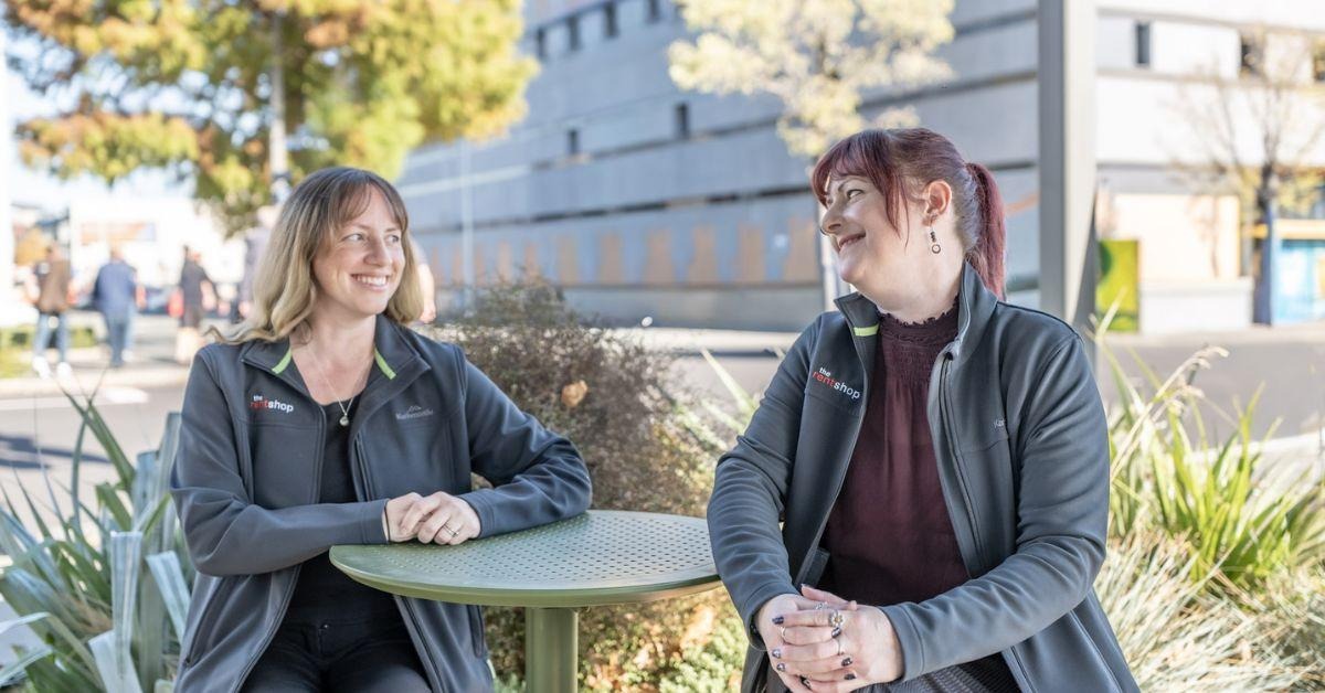 Two The Rent Shop property managers chatting at an outdoor table in spring