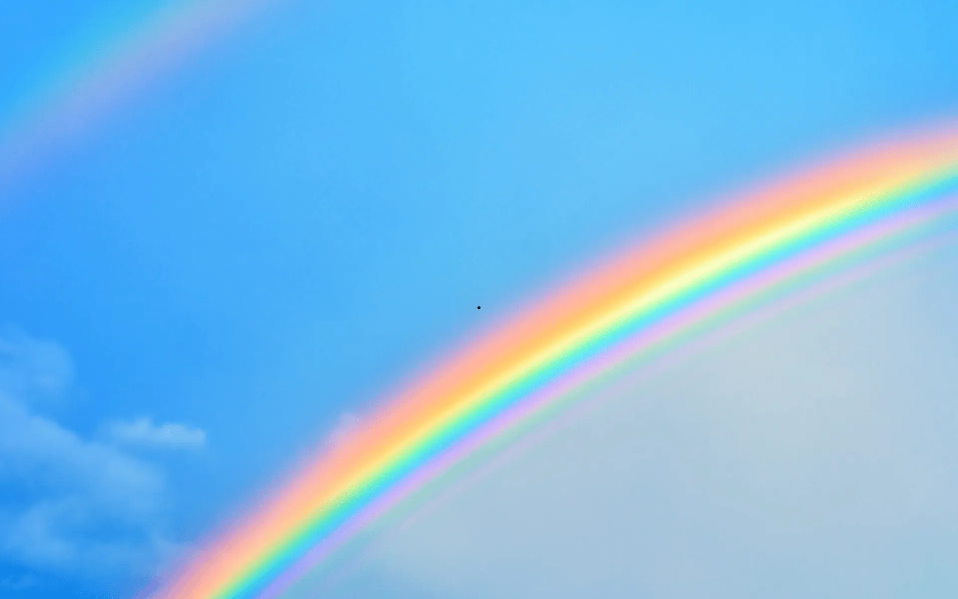 Das Bild zeigt einen blauen Himmel mit einem Regenbogen. 