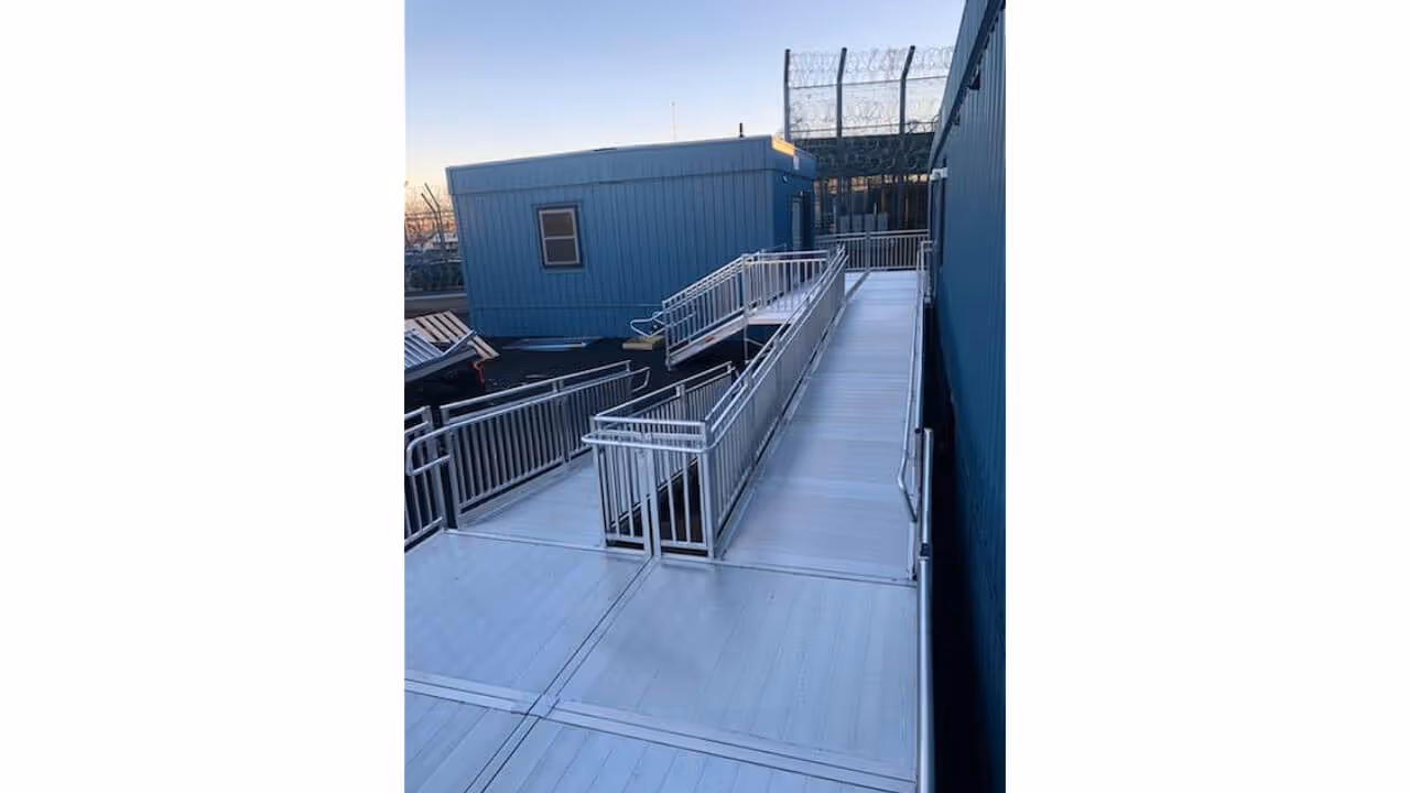 Outdoor stair lift mounted on a residential staircase with curved metal rail, designed for senior mobility and wheelchair accessibility in all weather conditions.