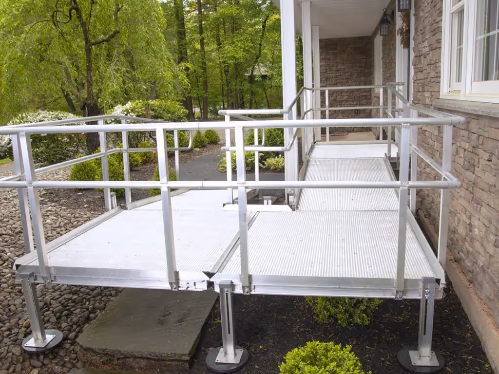 A metal platform ramp is installed outside a house, providing accessibility for individuals with mobility challenges.