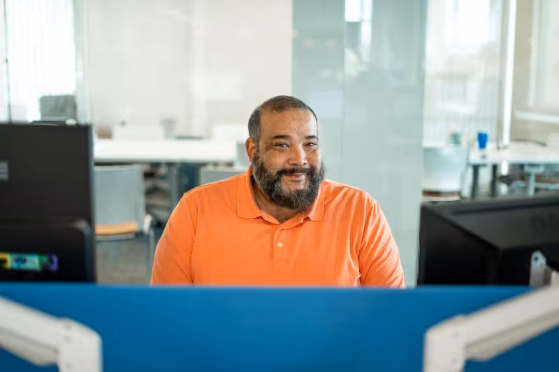A man sitting behind a desktop computer smiling