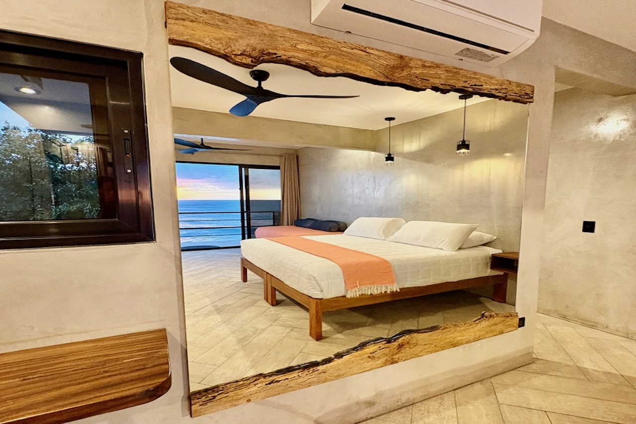 Interior of the Wave View Room at Miramar SurfCamp reflected in a wooden mirror with ocean view