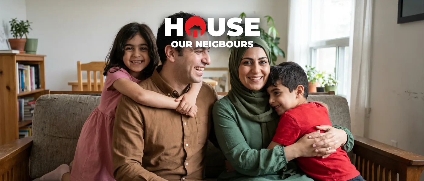 A joyful family of four embraces on a sofa in a cozy living room. Two children hug their smiling parents, creating a warm and inviting atmosphere.