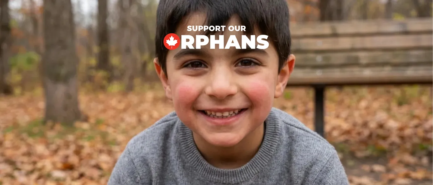 Young boy smiling warmly, wearing a gray sweater, sits on a bench in a park filled with autumn leaves. Text reads "Support Our Orphans."
