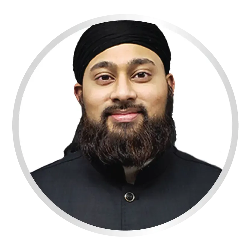 A man with a full beard wearing a black head covering and a black collared shirt smiles directly at the camera.