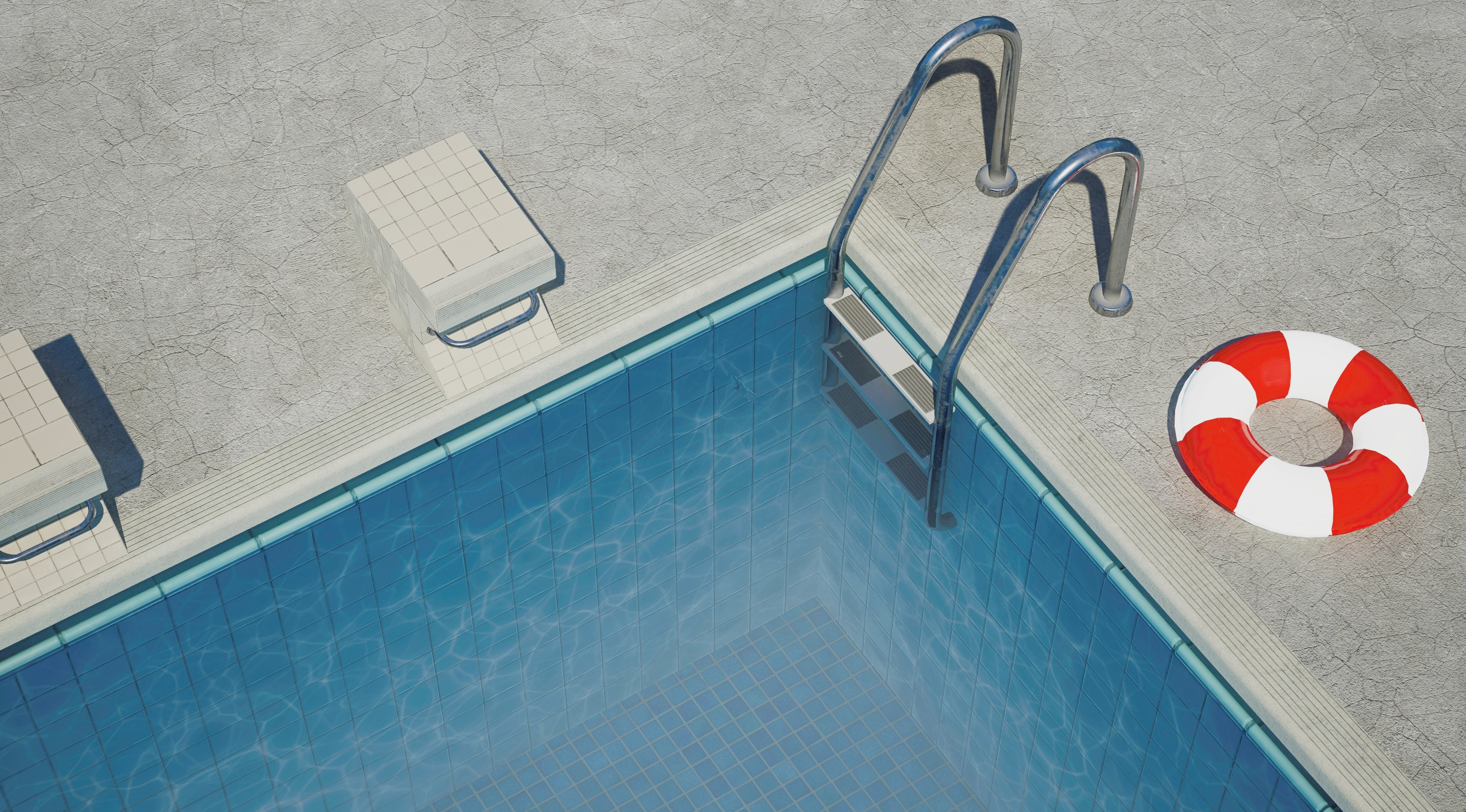 Poolrand eines Innenpools der zu Wohnraum umgenutzt werden soll mit rot weißem Schwimmring daneben.