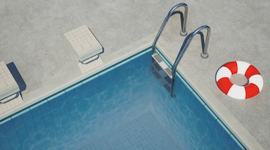 Poolrand eines Innenpools der zu Wohnraum umgenutzt werden soll mit rot weißem Schwimmring daneben.