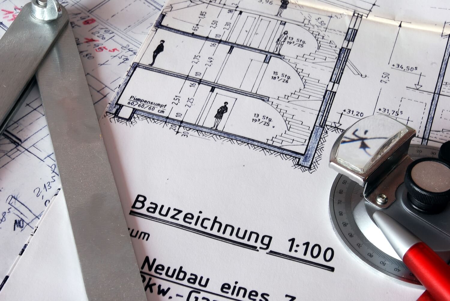 Technische Bauzeichnungen mit Messwerkzeugen wie Winkelmesser und Lineal, genutzt für die Planung und Ausarbeitung eines Standsicherheitsnachweises.