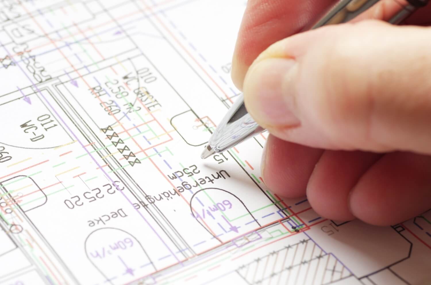 Detailaufnahme einer Hand, die technische Angaben in eine Bauzeichnung einträgt, als Teil der Erstellung eines Standsicherheitsnachweises.
