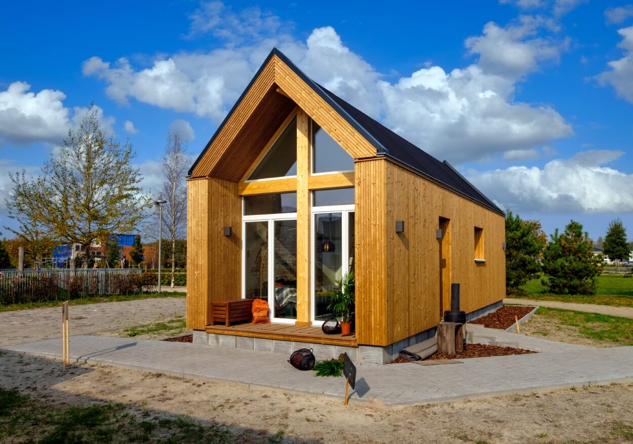 Tiny House aus Holz als dauerhafter Wohnsitz vor blauem Himmel