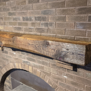 Reclaimed wood fireplace mantel on a brick wall.