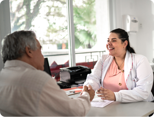 Healthcare worker observing a man using a standing medical scale in a clinical room.