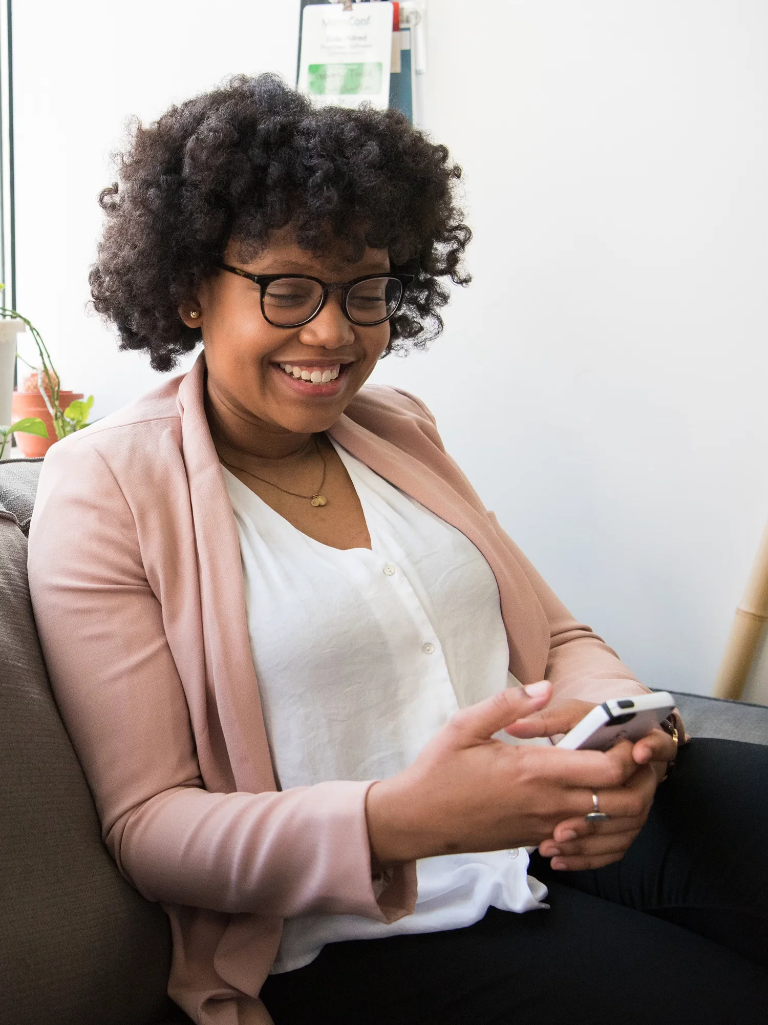 A woman is checking her phone and smiling widely.