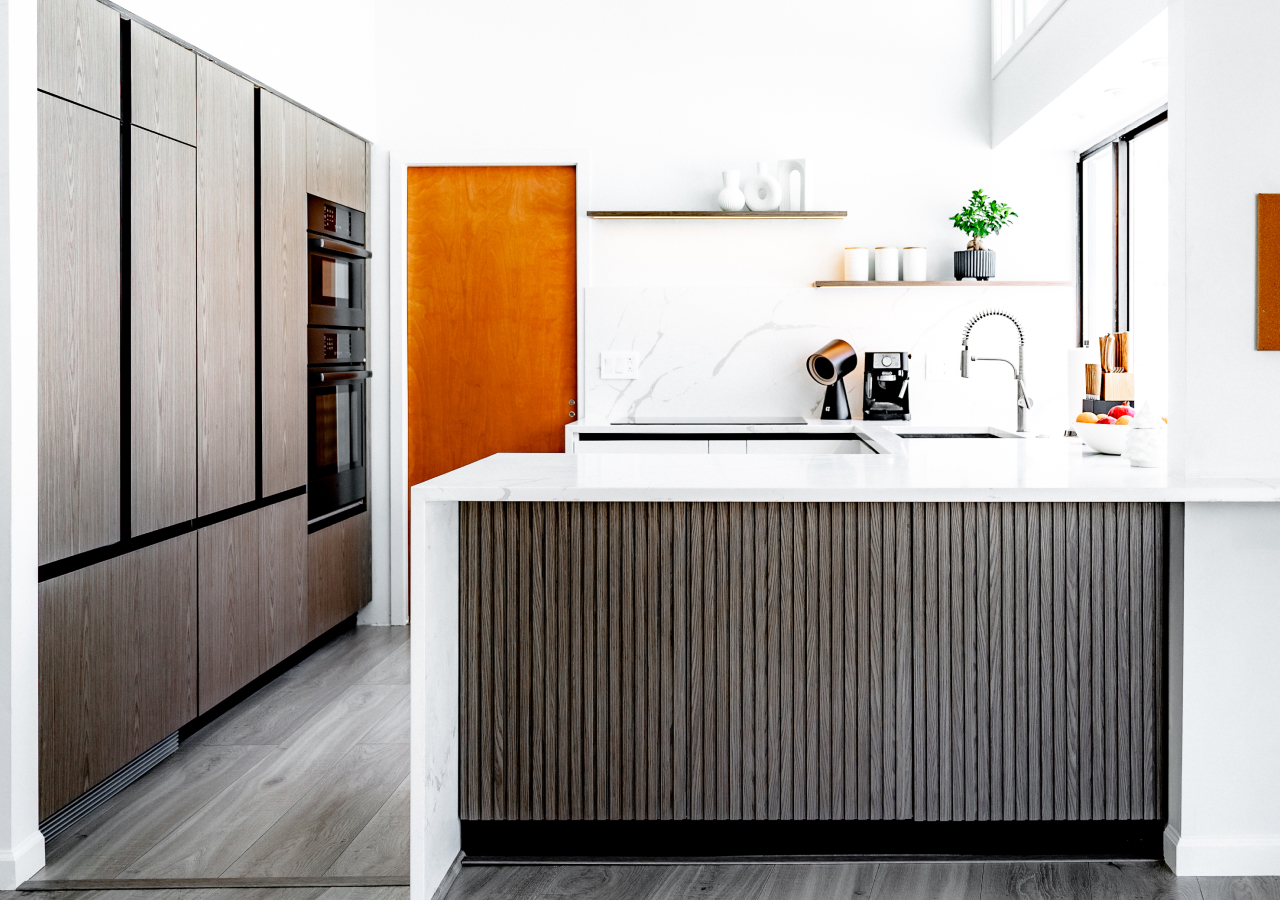 Scandinavian minimalist kitchen with fluted wood island, open shelving, built-in pantry ovens, and sleek white quartz countertops.
