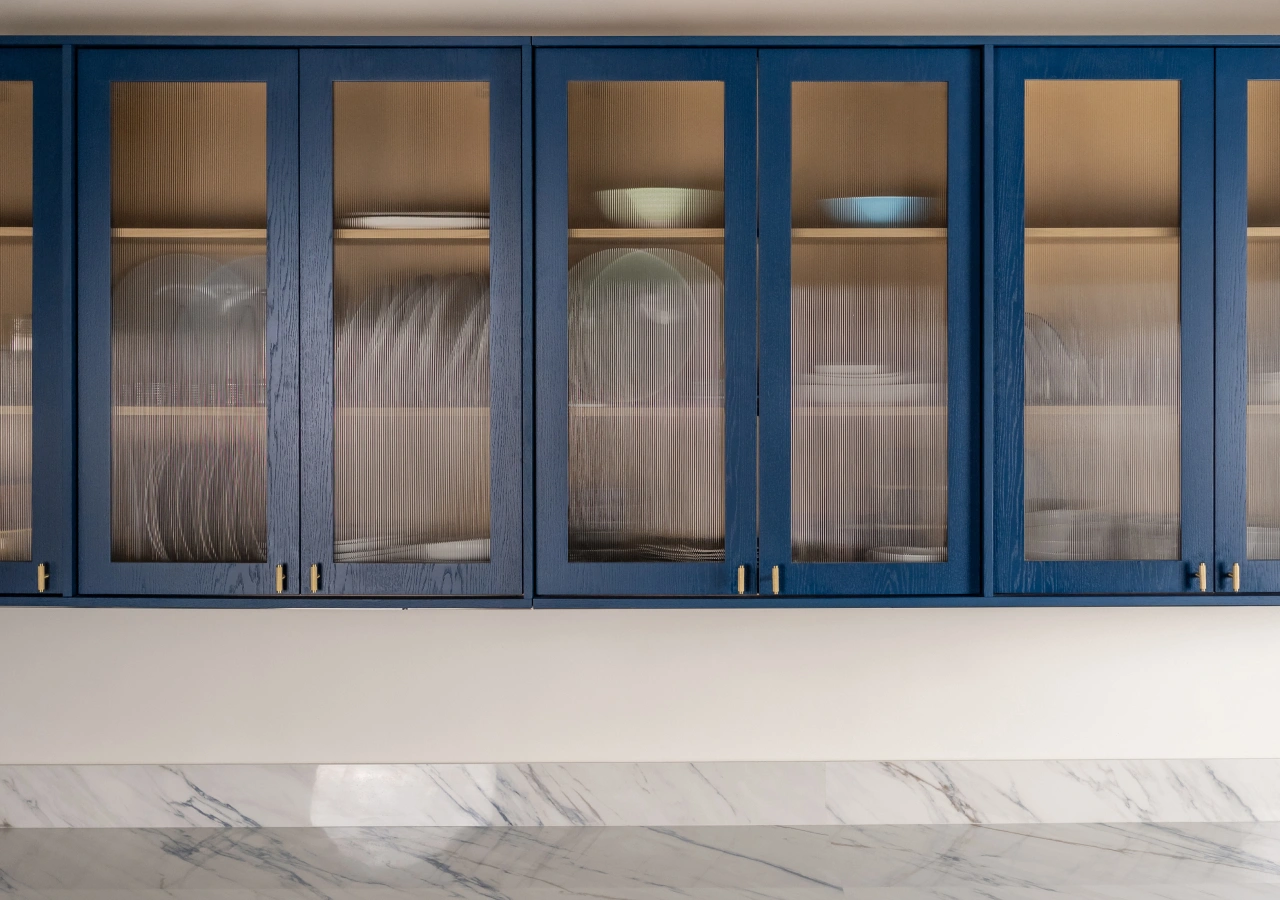 Navy blue glass-front wall cabinets with brass handles