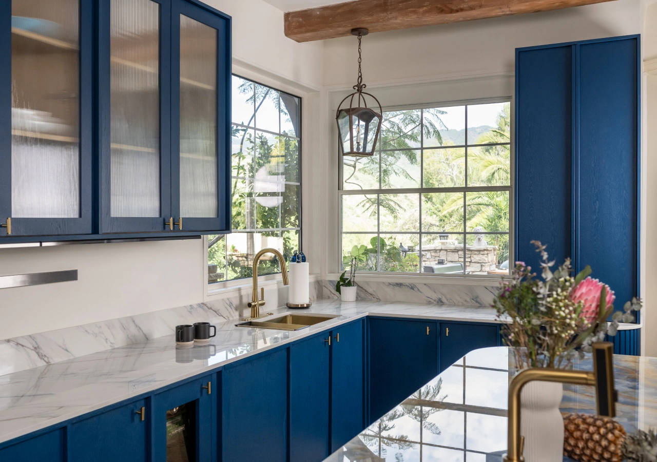 Navy blue kitchen with glass upper cabinets and a window