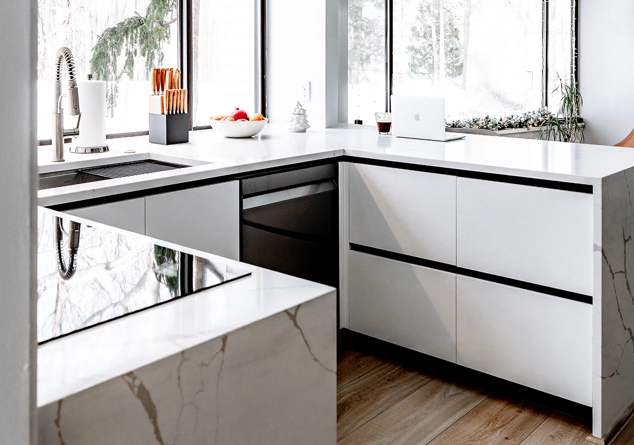 White handleless kitchen with a marble countertop and a window