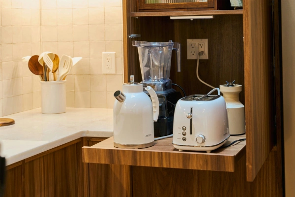 Walnut appliance garage open with a blender, kettle and toaster