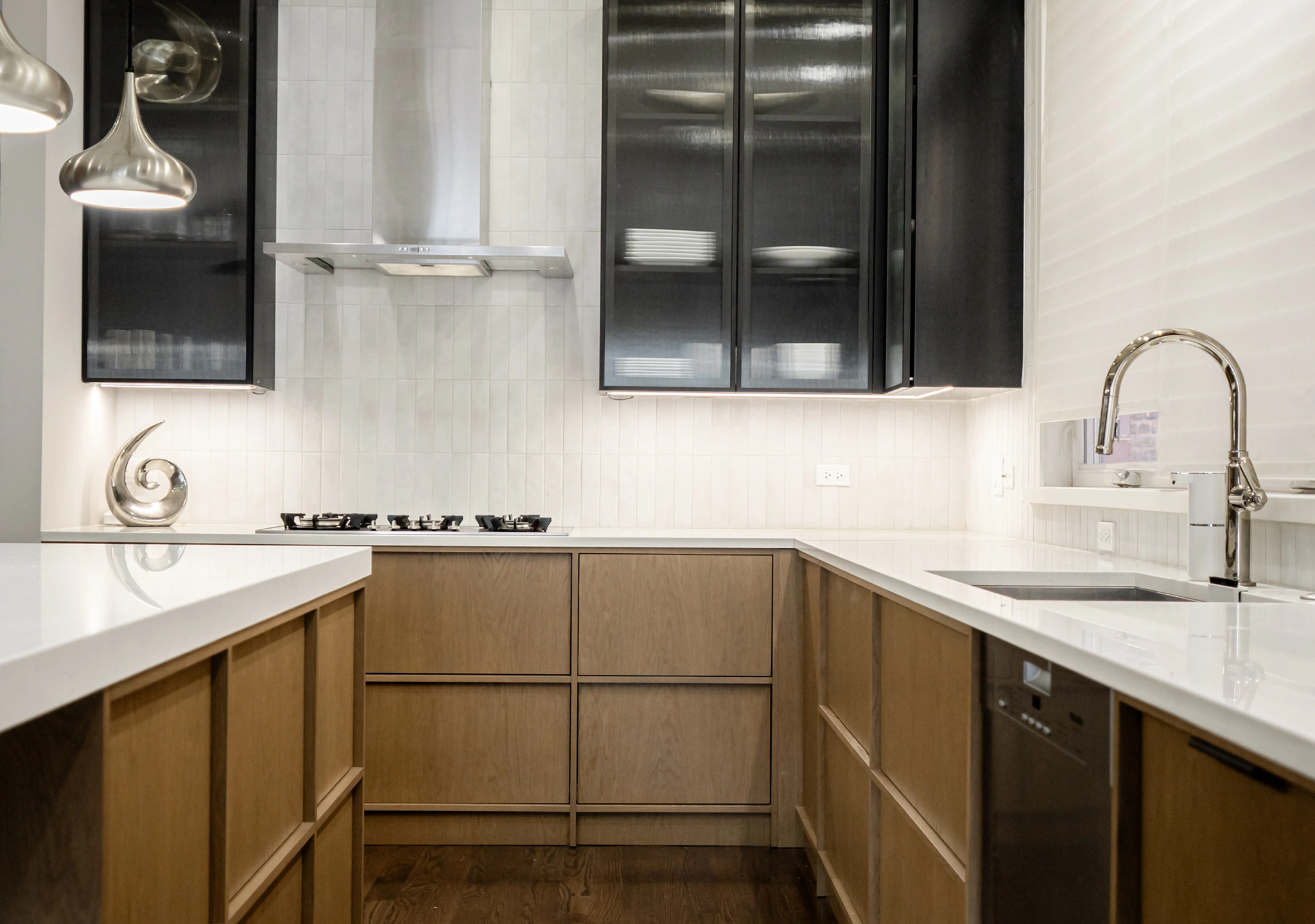 Oak kitchen with a white countertop, black uppers and a stainless steel sink