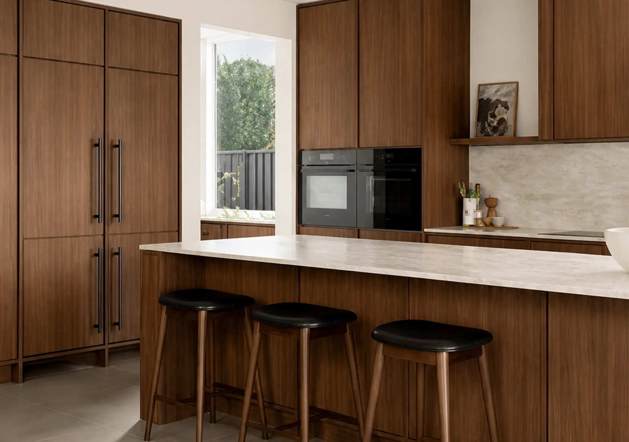Walnut-tone kitchen with a white island and black stools