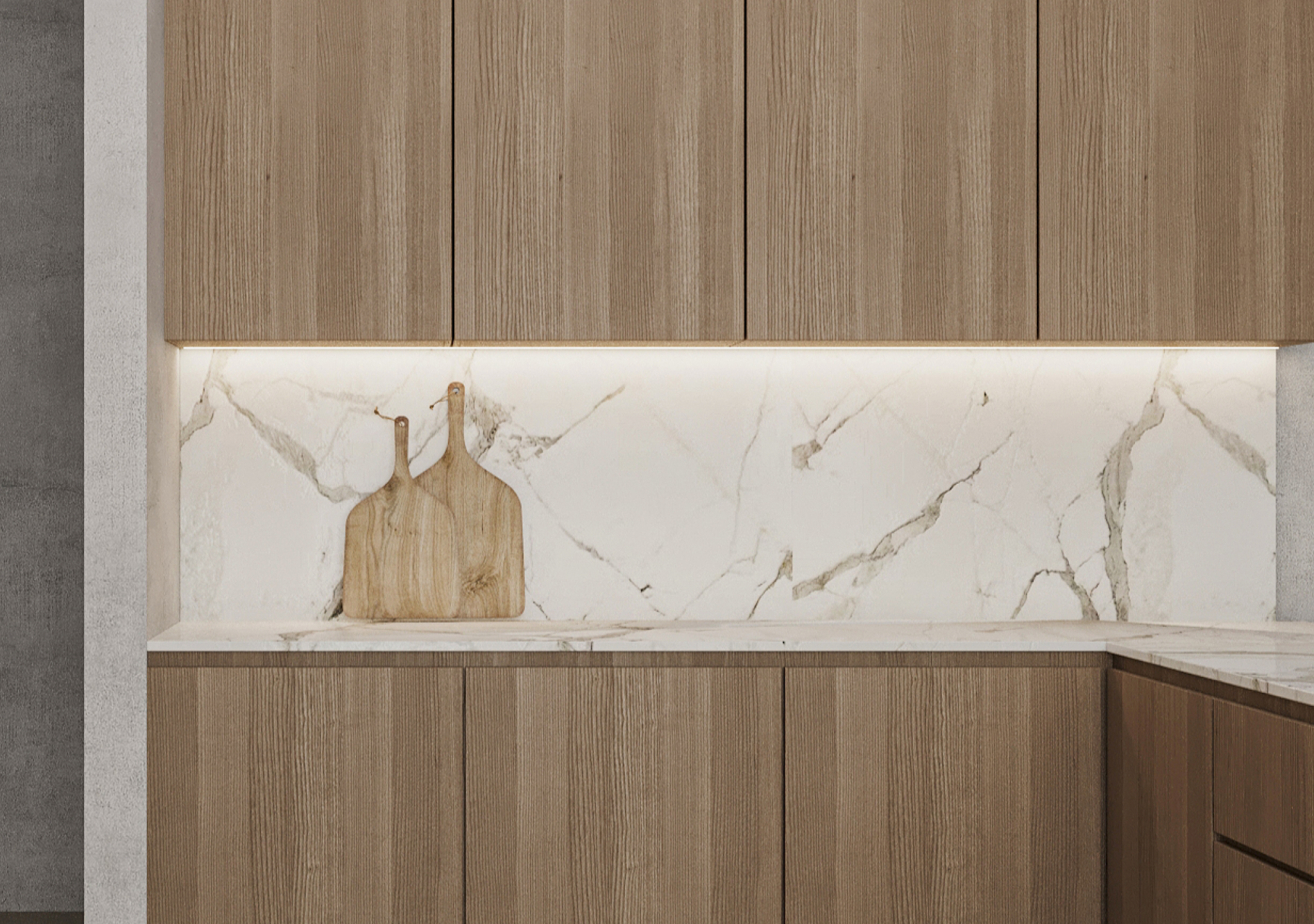 Light oak cabinets with a lit marble backsplash and two cutting boards