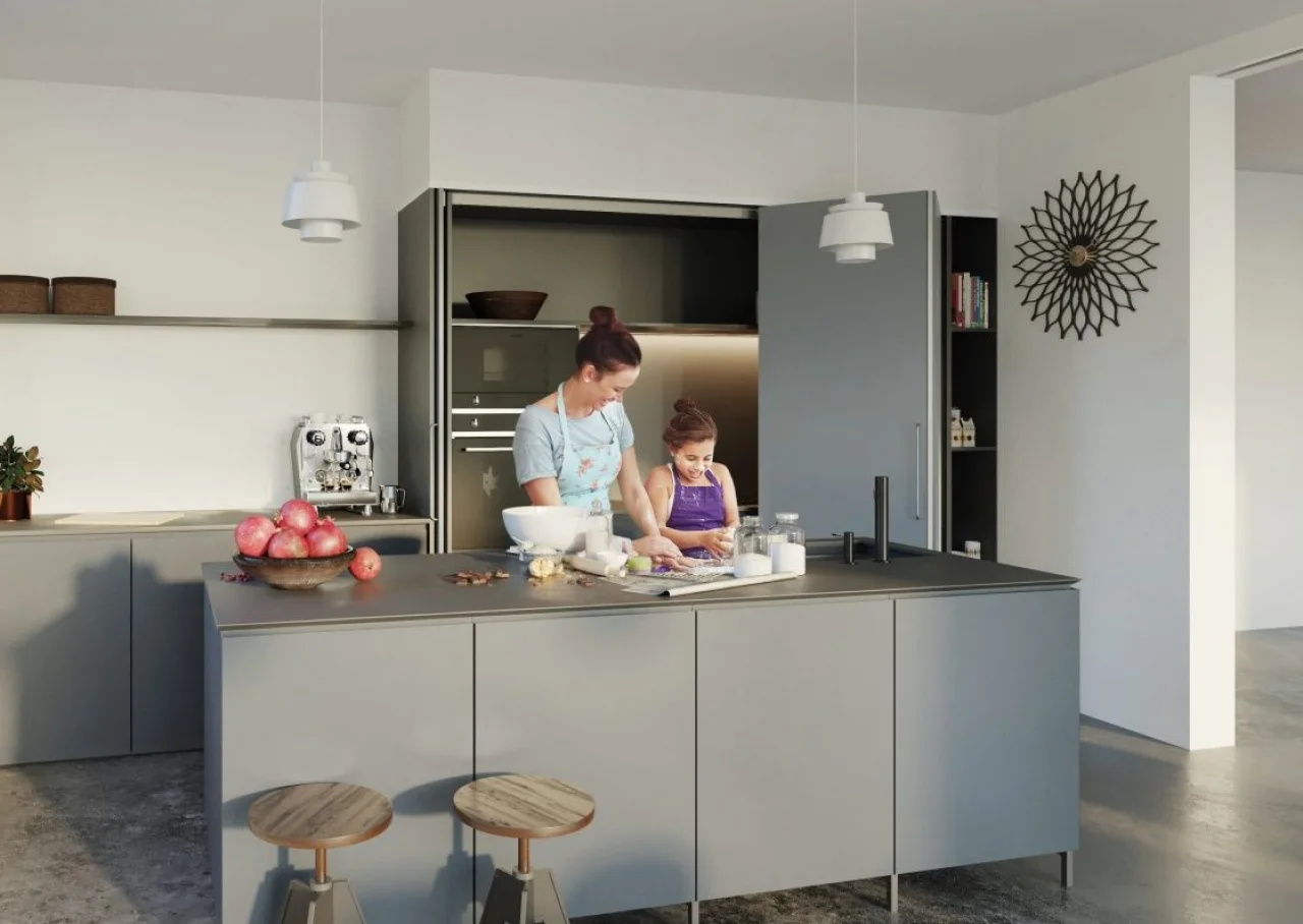 Grey kitchen with a pocket-door cabinet open and a person at the counter