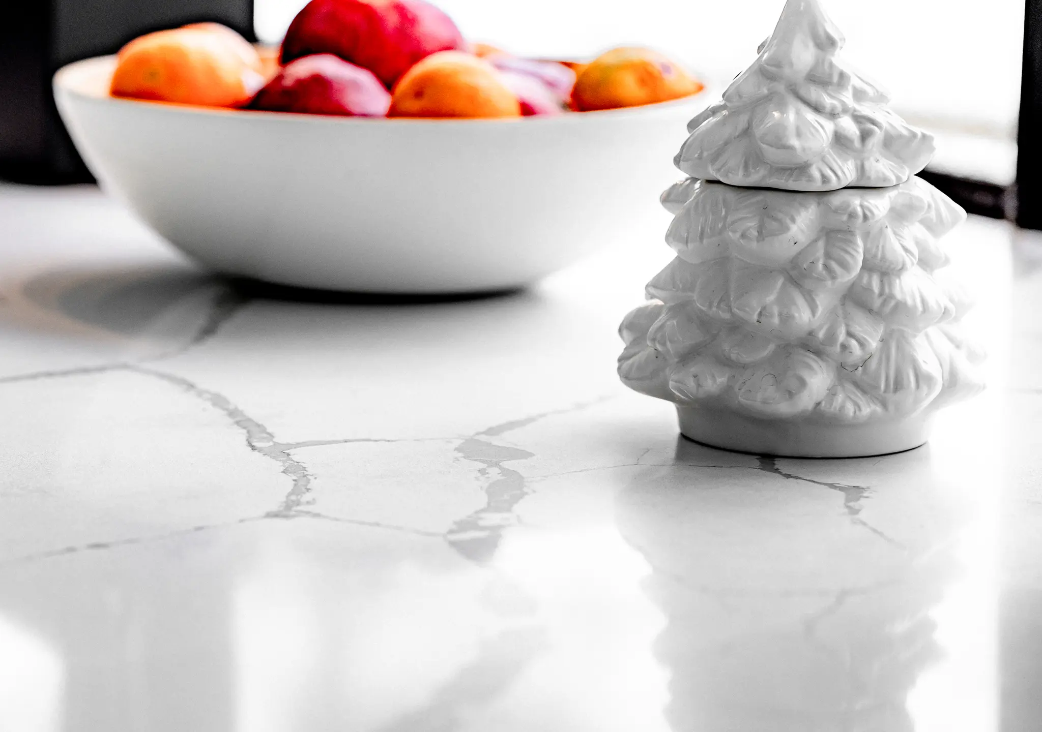 White quartz countertop with a bowl of fruit and a ceramic tree