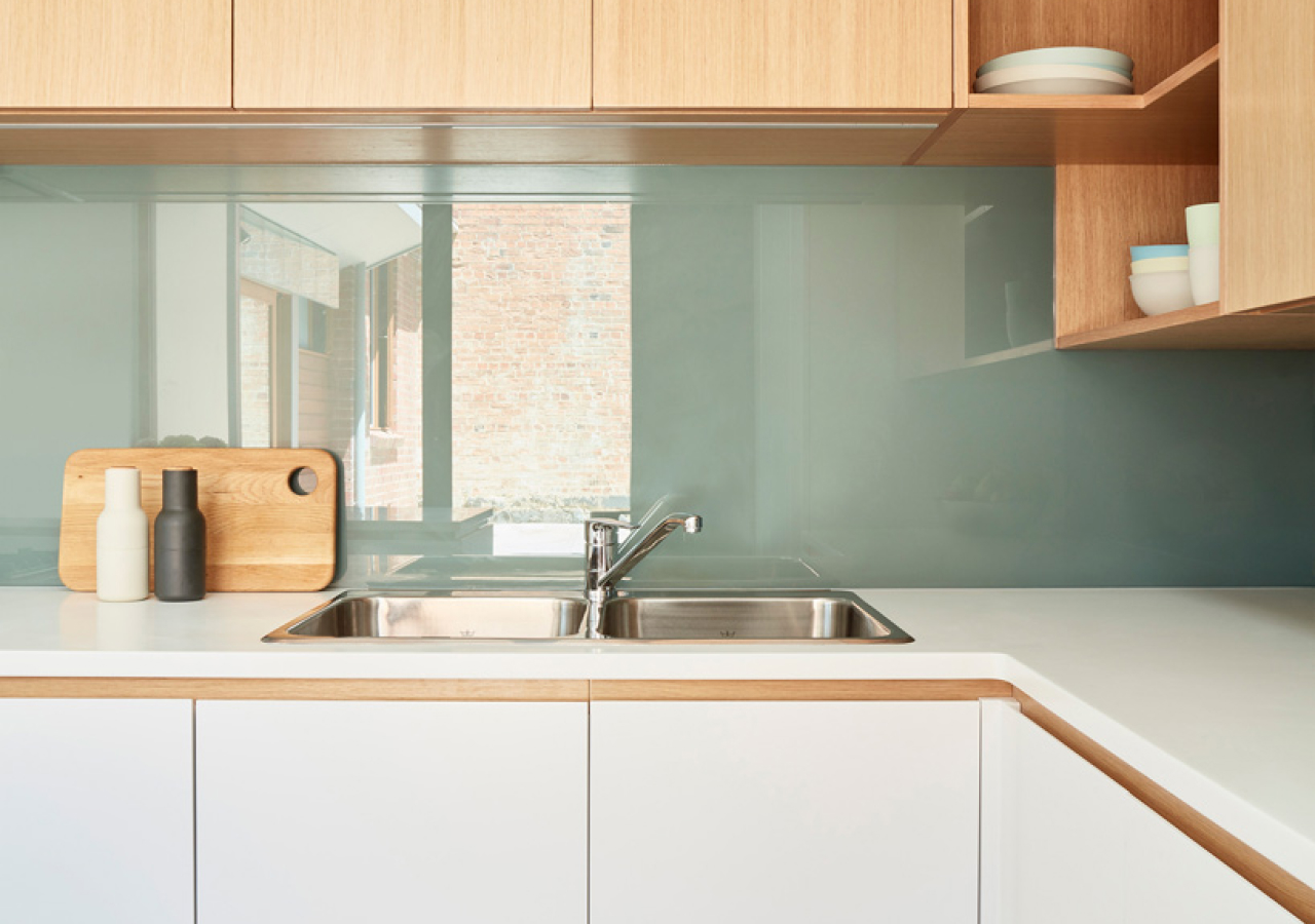 Light blue glass backsplash with a sink and a window