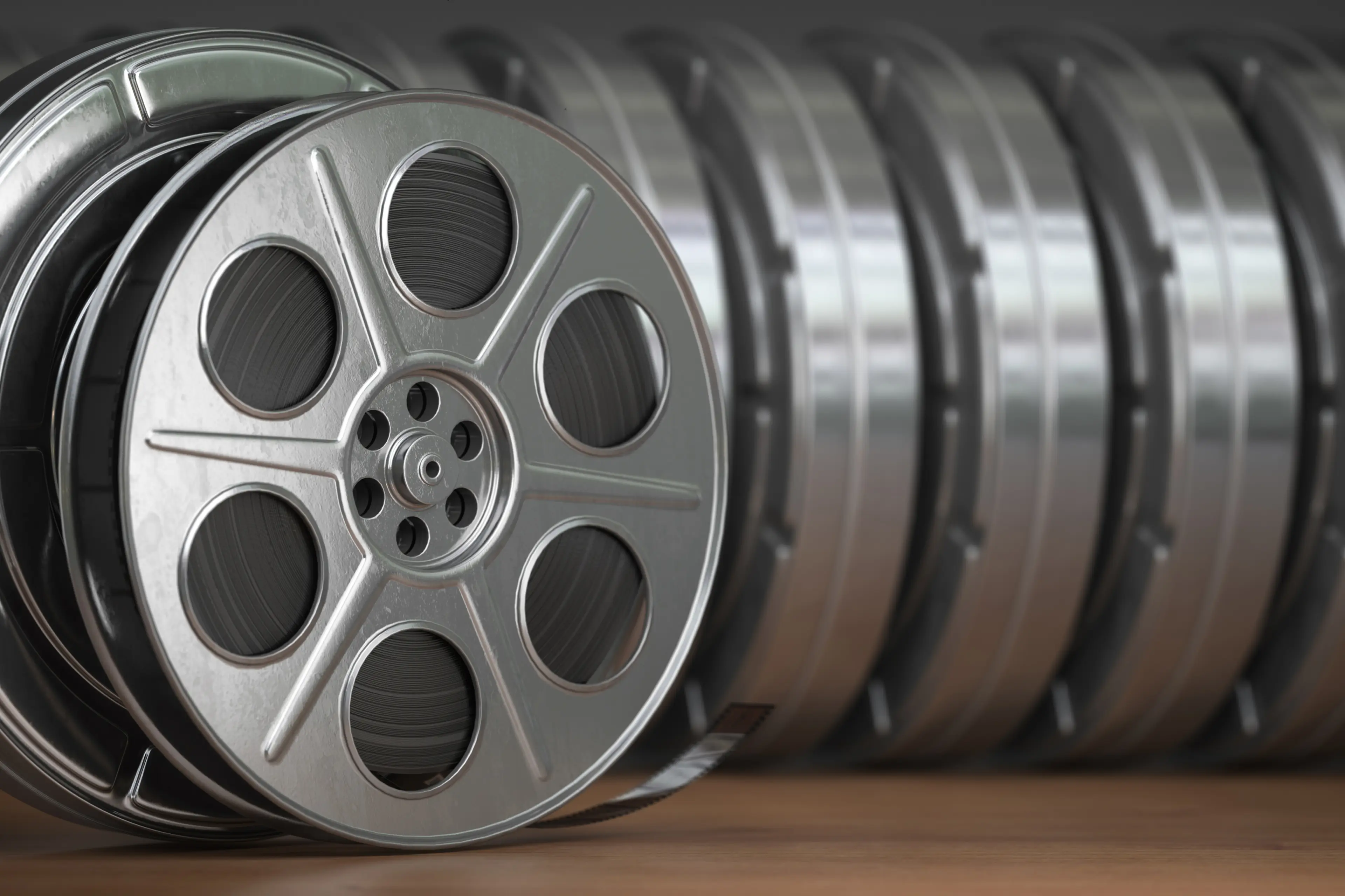 Close-up of stacked vintage metal film reels on a wooden surface.